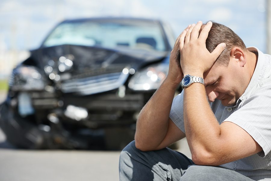Adult upset driver man in front of automobile crash car collisio man holding head in front of crashed vehicle - auto accident concept