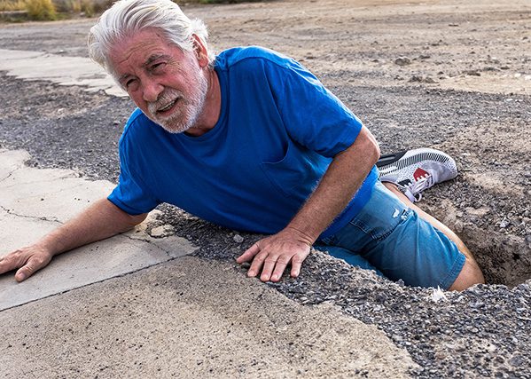 older man had a trip and fall accident with a large pothole