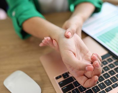 office worker with arthritis rubbing their wrist
