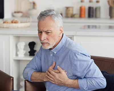 older man with heart disease grabbing his chest