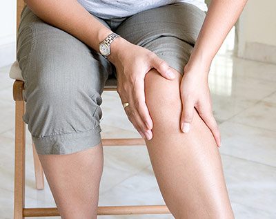 Person with hypermobility pain grabbing their knee