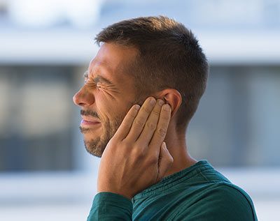 man in pain suffering from tinnitus